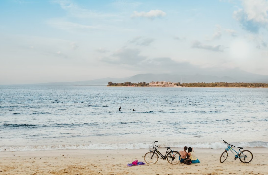 Семейные пары на пляже с велосипедом